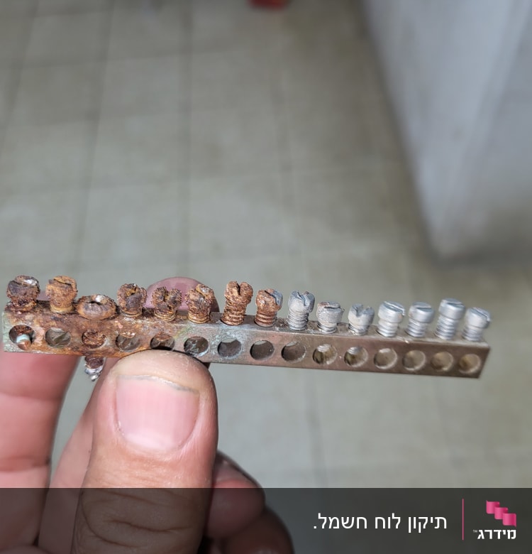 פס ברזל עם ברגים חלודים ביד חשמלאי